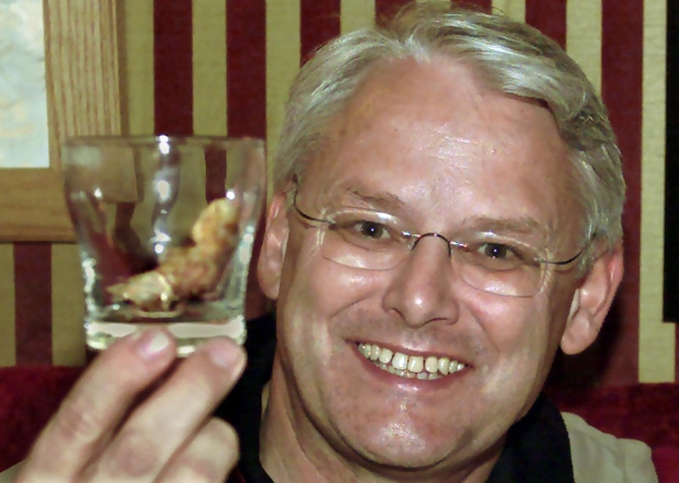 B.C. Premier Gordon Campbell smiles as he holds a pickled human toe into a cocktail glass of Yukon Jack Whiskey at the Sourdough Saloon in Dawson City, ... - image