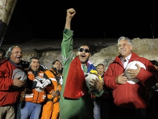 In this photo released by the Chilean Presidential Press Office, the last miner to be rescued, Luis Urzua, center, gestures as Chile's President Sebastian Pinera, right, looks on after his rescue from the collapsed San Jose gold and copper mine where he had been trapped with 32 other miners for over two months near Copiapo, Chile, Wednesday Oct. 13, 2010. (AP Photo/Alex Ibanez, Chilean Presidential Press Office)