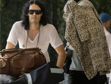 British actor-comedian Russell Brand, left, walks with his fiancee Katy Perry, her face covered with coat, after their arrival at the airport in Mumbai, India, Wednesday, Oct. 20, 2010. According to local reports, Brand and Perry are to be married later this week in the northern Indian town of Jaipur. (AP Photo/Rafiq Maqbool)