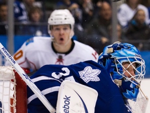 Toronto Maple Leafs goalie Jean-Sebastien Giguere, right, takes a puck of his helmet while playing against the Calgary Flames during third period NHL hockey action in Toronto on Saturday, January 15, 2011. THE CANADIAN PRESS/Nathan Denette