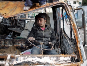 An anti-government protester sits inside a burnt out car near Tahrir Square, the center of anti-government demonstrations, in Cairo, Egypt, Sunday, Feb. 6, 2011. A sense of normalcy began to return to the capital of some 18 million people, which has been largely closed since chaos erupted shortly after the protests began on Jan. 25. (AP Photo/Tara Todras-Whitehill)