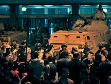 Army soldiers stand guard as anti-government protesters surround the state television building following Egyptian President Hosni Mubarak's televised speech, on the Corniche in downtown Cairo, Egypt, on Thursday, Feb. 10, 2011. Mubarak refused to step down or leave the country and instead handed his powers to his vice president. (AP Photo/Mohammed Abu Zaid)