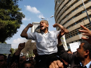 Public transportation workers protest in demand of salary raises in front of the national TV building, right, in Cairo, Egypt, Monday, Feb. 14, 2011. (AP / Khalil Hamra)