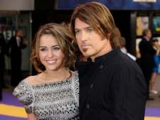 In this April 23, 2009, file photo, singer and actress Miley Cyrus, left, and her father Billy Ray Cyrus arrive for the British premiere of the film "Hannah Montana" at a Leicester Square cinema in London. (AP Photo/Joel Ryan)