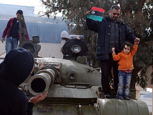 Libyans stand on an army tank at the state security camp in Benghazi, Libya, Tuesday, Feb. 22, 2011. Libyan leader Moammar Gadhafi vowed to fight on and die a "martyr," calling on his supporters to take back the streets from protesters demanding his ouster, shouting and pounding his fist in a furious speech Tuesday on state TV. (AP Photo/Alaguri)