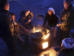 Survivors huddle around the open fire to keep warm at a shelter in Minamisanriku, Japan, on Friday, March 18, 2011, just one week after a massive earthquake and resulting tsunami. (AP Photo/Yomiuri Shimbun, Ichiro Ohara)