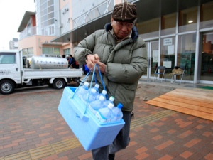 A man carries bottles of water filling up at a supply water tank in earthquake-damaged Urayasu, Japan, on Wednesday, March 23, 2011. A spike in radiation levels in Tokyo's tap water spurred new fears about food safety in Japan. (AP Photo/ Lee Jin-man)