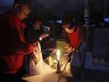 A cashier uses a calculator with a candle light at a supermarket as a blackout continues since Thursday night's strong aftershock in Tome, Miyagi Prefecture, Japan, Friday, April 8, 2011. The aftershock ripped through northeastern Japan, killing two people, knocking out power to vast areas Friday and piling misery on a region still buried under the rubble of last month's devastating tsunami. (AP Photo/Yomiuri Shimbun, Hiroshi Adachi)
