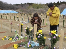 Kiyoko Takahashi, 81, holds a moment of silence on a burial ground at 2:46 p.m., exactly a month after a massive earthquake struck the area in Higashimatsushima, Japan, Monday, April 11, 2011. Takahashi lost her sister in the March 11 earthquake. (AP Photo/Yomiuri Shimbun, Kota Kawasaki)