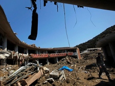 In this April 5, 2011 photo, a man walks through the debris at Okawa Elementary School, devastated by the March 11 earthquake and tsunami, in Ishinomaki, Miyagi Prefecture, northern Japan. The March 11 tsunami killed 74 of the 108 students at Okawa Elementary School and all but one of the dozen teachers. The main building is ripped open, with trees jammed into second floor classrooms, and the gym and playground have been reduced to muddied concrete foundations. (AP Photo/Vincent Yu)