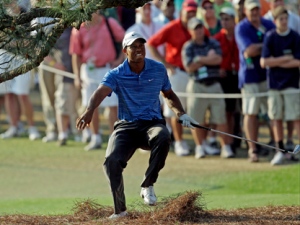 This April 9, 2011, file photo shows Tiger Woods nearly falings backwards after hitting out of the rough on the 17th hole during the third round of the Masters golf tournament, in Augusta, Ga. Woods has what he calls a minor knee injury and will miss the Wells Fargo Championship next week at Quail Hollow. He hopes to return in a few weeks.Woods says on his website that he has mild sprains of a ligament in his left knee and left Achilles' tendon. He hurt himself while hitting from an awkward lie on the 17th hole during the third round of the Masters. (AP Photo/Chris O'Meara, File)