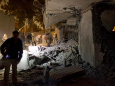 In this photo made on a government organized tour, government officials and members of the media gather at the site of a NATO missile strike that killed Gadhafi's youngest son and three grandchildren and wounded friends and relatives, in Tripoli, Libya, Saturday, April 30, 2011. Libyan leader Moammar Gadhafi survived attack, Libya's spokesman said. (AP Photo/Darko Bandic)