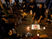 A small group sits with candles and a sign as they react to the news of Osama Bin Laden's death on Vesey Street, near ground zero, during the early morning hours of Monday, May 2, 2011 in New York. President Barack Obama announced Sunday night that Osama bin Laden was killed in an operation led by the United States. (AP Photo/Jason DeCrow)