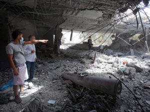 In this photo made on a government organized tour, Libyans inspect damage while standing next to an unexploded missile at the Gadhafi family compound in a residential area of Tripoli, Libya, Sunday, May 1, 2011. Libyan leader Moammar Gadhafi escaped a NATO missile strike in Tripoli that killed one of his sons and three young grandchildren, a government spokesman said early Sunday. (AP Photo/Darko Bandic)