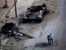 In this photo taken Monday, May 23, 2011, men walk next to a destroyed tank in Tripoli Street, the centre of fighting between forces loyal to Libyan leader Moammar Gadhafi and rebels, in downtown Misrata, Libya. (AP Photo/Rodrigo Abd)In this photo taken Monday, May 23, 2011, men walk next to a destroyed tank in Tripoli Street, the centre of fighting between forces loyal to Libyan leader Moammar Gadhafi and rebels, in downtown Misrata, Libya. (AP Photo/Rodrigo Abd)