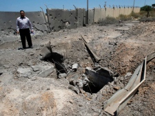 In this photo taken on a government organized tour a Libyan official stands next to a crater at a gas production plant outside the town of Janzour, near Tripoli, Libya, Monday, June 13, 2011. The facility near the town of Janzour was struck by a NATO bomb on Saturday evening, according to plant's director. The plant was located next to what appeared to be a military facility that had itself been previously bombed. Outside a gate to the complex, about 30 yards from the gas plant blast site, sat several damaged tanks and other military vehicles. (AP Photo/Ivan Sekretarev)