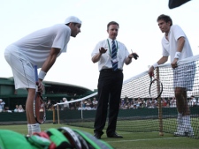 This June 23, 2010, file photo shows referee Soeren Friemel, calling off the record-breaking men's singles match between John Isner of the U.S., left, and Nicolas Mahut of France, because of bad light, at the All England Lawn Tennis Championships at Wimbledon. No other match had lasted longer than 6 hours, 33 minutes, a time Isner and Mahut surpassed by more than 4� hours. (AP Photo/Alastair Grant, File)