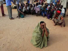 A Somali woman sits alone as male refugees line up to register as new arrivals at Dagahaley Camp, outside Dadaab, Kenya, Thursday, July 14, 2011. East Africa's drought is battering Somali children, hundreds of whom have been left for dead on the long, dry journey to the world's largest refugee complex in Dadaab, northern Kenya. UNICEF on Thursday called the drought and refugee crisis "the most severe humanitarian emergency in the world." (AP Photo / Rebecca Blackwell)