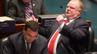 Toronto Mayor Rob Ford makes a drinking and driving gesture to Coun. Paul Ainslie in the council chamber as councillors consider a motion to limit the mayor's powers Monday, Nov. 18, 2013. (The Canadian Press/Chris Young)
