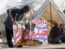 An Egyptian protester puts up a poster against ousted Egyptian president Hosni Mubarak, seen left on poster, and Field Marshal Mohamed Hussein Tantawi, head of Egypt's ruling military council, outside his tent at Tahrir Square, the focal point of Egyptian uprising, in Cairo, Egypt, on Sunday, July 24, 2011. (AP Photo/Amr Nabil)