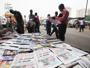 People gather to read local newspapers carrying headlines about the 50 people crushed to death in Lagos, Nigeria, Wednesday, Aug. 3, 2011. Police report that robbers stopped an overnight bus early Tuesday at Kabba junction leading to Abuja, Nigeria, and forced the passengers to disembark and lie down in the road, when another bus ran them over, killing at least 14 people. Police spokesman Ajayi Okasanmi said Wednesday that the bus ran over the people but did not stop at the scene, and that dozens of other passengers are still missing. (AP Photo/Sunday Alamba)