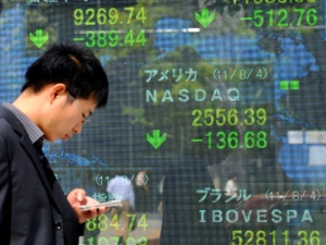 A man walks by stock indicators in downtown Tokyo on Friday Aug. 5, 2011. Asian stock markets are tumbling amid fears the U.S. may be heading back into recession and Europe's debt crisis is worsening. (AP Photo/Kyodo News)