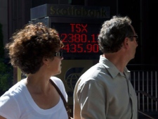 People walk past the TSX sign as it hit a negative 435.90 points in Toronto on Thursday, August 4, 2011. (THE CANADIAN PRESS/Nathan Denette)