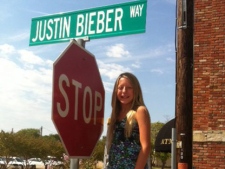 In this photo provided by the City of Forney, Texas, "mayor for a day" Caroline Gonzalez, age 11, of Forney, poses at the temporary sign she had posted Tuesday, Aug. 16, 2011 to make part of Main Street "Justin Bieber Way" for the day she "held" office. Gonzalez won a contest meant to get young people interested in municipal government. (AP Photo/City of Forney, Jeff Crilley)