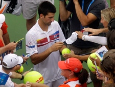 Novak Djokovic, from Serbia, signs autographs for fans after Tomas Berdych, from the Czech Republic, retired with an injury and Djokovic leading 7-5 in a semifinal match at the Western & Southern Open tennis tournament, Saturday, Aug. 20, 2011 in Mason, Ohio. (AP Photo/Al Behrman)