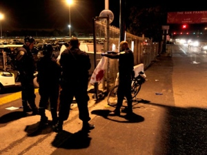 A police officer holds up a bloodied shirt as they investigate the scene of a shooting just outside of lot L at Candlestick Park, where the San Francisco 49ers had just finished playing the Oakland Raiders in San Francisco, Calif. on Saturday Aug. 20, 2011. (AP Photo/Michael Macor - San Francisco Chronicle)