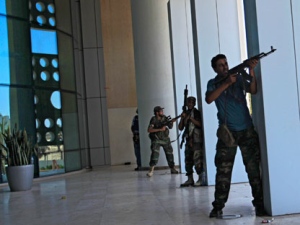 Rebel fighters take shelter as an intense gunbattle erupted outside the Corinthia hotel, where many foreign journalists are staying, in Tripoli, LIbya, Thursday, Aug. 25, 2011. Libya's rebel leadership has offered a 2 million dollar bounty on Gadhafi's head, but the autocrat has refused to surrender as his 42-year regime crumbles, fleeing to an unknown destination. Speaking to a local television channel Wednesday, apparently by phone, Gadhafi vowed from hiding to fight on "until victory or martyrdom." (AP Photo/Sergey Ponomarev)