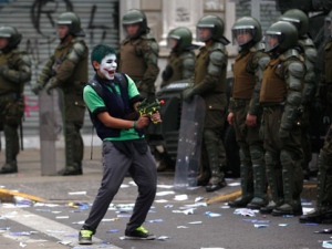 A demonstrator points a toy gun at a line of riot police on the second day of a national strike in Santiago, Chile, Thursday Aug. 25, 2011. Chileans marched Thursday, demanding profound changes in the country's heavily centralized and privatized form of government. Union members, students, government workers and Chile's center-left opposition parties joined the nationwide two-day strike. (AP Photo/Roberto Candia)