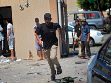 A Libyan man runs across the street seeking shelter from sniper fire in Tripoli, Libya, Friday, Aug. 26, 2011. (AP Photo/Sergey Ponomarev)