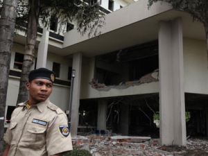 An unidentified security officer stands outside at the United Nation's office Saturday, Aug. 27, 2011 in Abuja, Nigeria following Friday's car bomb. Nigeria's president says his government will bring terrorism "under control," the day after a car bomb at United Nations headquarters in Abuja killed at least 18 people. President Goodluck Jonathan said Saturday during a visit to the site: "As a government we are working on it, and we will bring it under control." (AP Photo/Sunday Alamba)