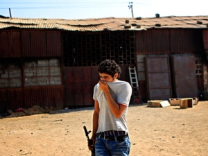 A rebel fighter covers his face against the smell as he walks near a warehouse containing the remains of at least 50 burned bodies in Tripoli, LIbya, Sunday, Aug. 28, 2011. A survivor said they were civilians killed by pro-Gadhafi soldiers. (AP Photo/Sergey Ponomarev)