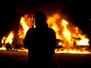 A report into Vancouver's Stanley Cup riot is set for release Thursday, examining what factors led to the chaos that followed the Canucks loss to the Boston Bruins and how to prevent it from happening again. A riot officer watches as two police cars burn during a riot in downtown Vancouver, Wednesday, June 15, 2011 following the Vancouver Canucks 4-0 loss to the Boston Bruins in game 7 of the Stanley Cup hockey final. (THE CANADIAN PRESS/Ryan Remiorz)
