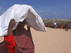 A Somali women carries away donated rations of food aid from UNHCR 1st May camp in Mogadishu Wednesday, Aug. 31, 2011. Somalia's famine refugees are celebrating the Muslim holiday of Eid al-Fitr, which ends a month of fasting, with the food rations distributed by aid agencies for their survival. Eid al-Fitr is traditionally celebrated with grand feasts in which delicacies are in abundance after fasting. (AP Photo/Khalil Senosi)