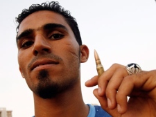 A Libyan youth poses with a bullet in the streets of Tripoli, Libya, Saturday, Sept. 3, 2011. Rebel fighters have advanced to within 10 kilometers (six miles) of one of Moammar Gadhafi's last strongholds, the town of Bani Walid, without encountering resistance. Despite Saturday's push forward, rebel officials say they're still trying to persuade tribal elders in Bani Walid to surrender without a fight. AP reporters traveling with the rebels approaching from the north came to within 10 kilometers of Bani Walid, which is about 90 miles (140 kilometers) southeast of Tripoli. (AP Photo/Francois Mori)