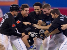 Toronto Blue Jays players celebrate with Adam Lind (centre) after he grounded into fielders choice for Mike McCoy to score against Los Angeles Angels during the 10th inning of MLB baseball action in Toronto on Monday, Sept. 19, 2011. (THE CANADIAN PRESS/Chris Young)