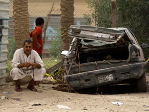 A man sits next to his damaged car at the scene of a car bomb attack in a town just outside Hillah, about 60 miles (95 kilometers) south of Baghdad, Iraq, Saturday, Oct. 1, 2011. The car bomb exploded Friday near a Shiite mosque where mourners had gathered for a funeral, killing and wounding scores of people, police said. The mosque as well as a nearby holy Shiite shrine. (AP Photo / Khalid Mohammed) 