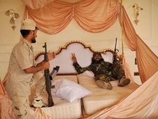 Libyan rebels rest in the bed of their country's ousted leader Moammar Gadhafi in a palace in Sirte, Libya, Monday, Oct. 10, 2011. Rebel forces have besieged Sirte since mid September and still facing fierce resistance from loyalists while trying to control Gadhafi's home town. (AP Photo/Bela Szandelszky)