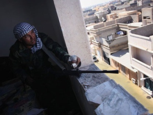 A revolutionary fighter fires his machine gun towards loyalist positions in Sirte, Libya, Wednesday, Oct. 12, 2011. Libya's de facto leader said Wednesday he is optimistic the ex-rebels will declare total victory over forces loyal to Moammar Gadhafi in less than a week, opening the way for a new transitional government to be formed within a month. (AP Photo/Manu Brabo)