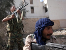 Revolutionary fighters fire at Gadhafi loyalist positions in downtown Sirte, Libya, Tuesday, Oct. 18, 2011. About 1,000 Libyan revolutionary troops have launched a major assault on Moammar Gadhafi's hometown, surging from the east to try to capture the last area under loyalist control. (AP Photo/Manu Brabo)