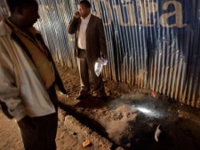 A shoe lies on the ground as a forensics worker shines his torch on a red flag marking evidence found at the scene of a blast in downtown Nairobi, Kenya, late Monday, Oct. 24, 2011. An explosion went off near a crowded bus stop Monday evening as people sought rides home, killing at least one person and wounding eight in the second blast of the day in Kenya's capital, twin assaults that came two days after the U.S. warned of possible terror attacks. (AP Photo/Ben Curtis)