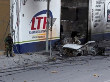 A soldier stands next to a car destroyed by an explosion in Monterrey, Mexico, Thursday Oct. 20, 2011. Mexican authorities say an apparent car bomb exploded in the northern city of Monterrey seconds before a military convoy passed by it, and no one was injured. (AP Photo/Hans-Maximo Musielik)
