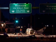 Investigators look over the wreckage of a passenger plane that crashed on a road while on approach to Vancouver International Airport in Richmond, B.C., on Thursday October 27, 2011. (THE CANADIAN PRESS/Darryl Dyck)