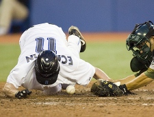 Toronto Blue Jays' David Eckstein, left, slides in to score as the ball gets away from Oakland A's catcher Kurt Suzuki. THE CANADIAN PRESS/Frank Gunn