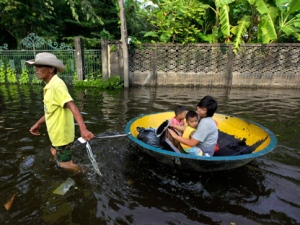 A Thai man pulls a makeshift boat to carry a his family through a flooded street in Bangkok, Thailand, Saturday, Nov. 5, 2011. Floodwaters lapped Bangkok's largest outdoor market Saturday as officials warned that there were no major barriers between the water and the heart of the Thai capital, less than 6 miles (10 kilometers) away. (AP Photo/Altaf Qadri)