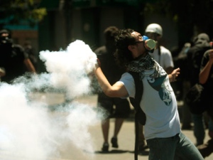 A masked student sends back a tear gas canister lanced by riot police during clashes in Valparaiso, Chile, Wednesday Nov. 9, 2011. Thousands of students seeking education reforms marched Wednesday to coincide with the start of the 2012 budget talks in the legislature. Congressional leaders and a representative group of students were to meet for the first time since the protests began. (AP Photo/Luis Hildalgo)