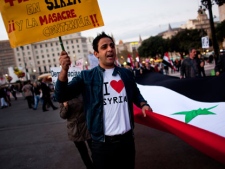 Anti-Syrian regime protesters shout slogans against Syrian President Bashar Assad during a protest in Barcelona, Spain, on Saturday, Nov. 12, 2011. The Arab League voted Saturday to suspend Syria in four days and warned the regime could face sanctions if it does not end its bloody crackdown against anti-government protesters. The decision was a symbolic blow to a nation that prides itself on being a powerhouse of Arab nationalism. The banner reads in Spanish, "And the massacre continues in Syria". (AP Photo/Emilio Morenatti)